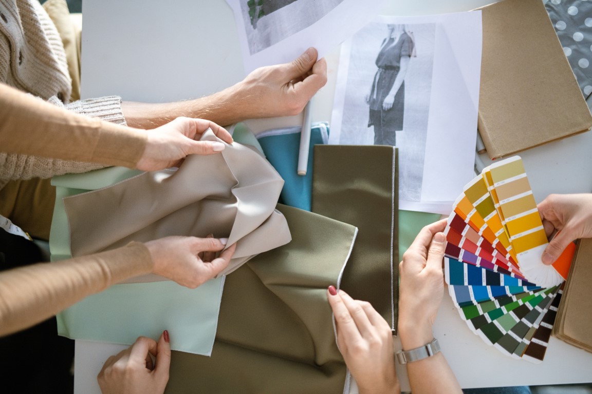 Hands of creative designers choosing fabric and color for new fashion collection