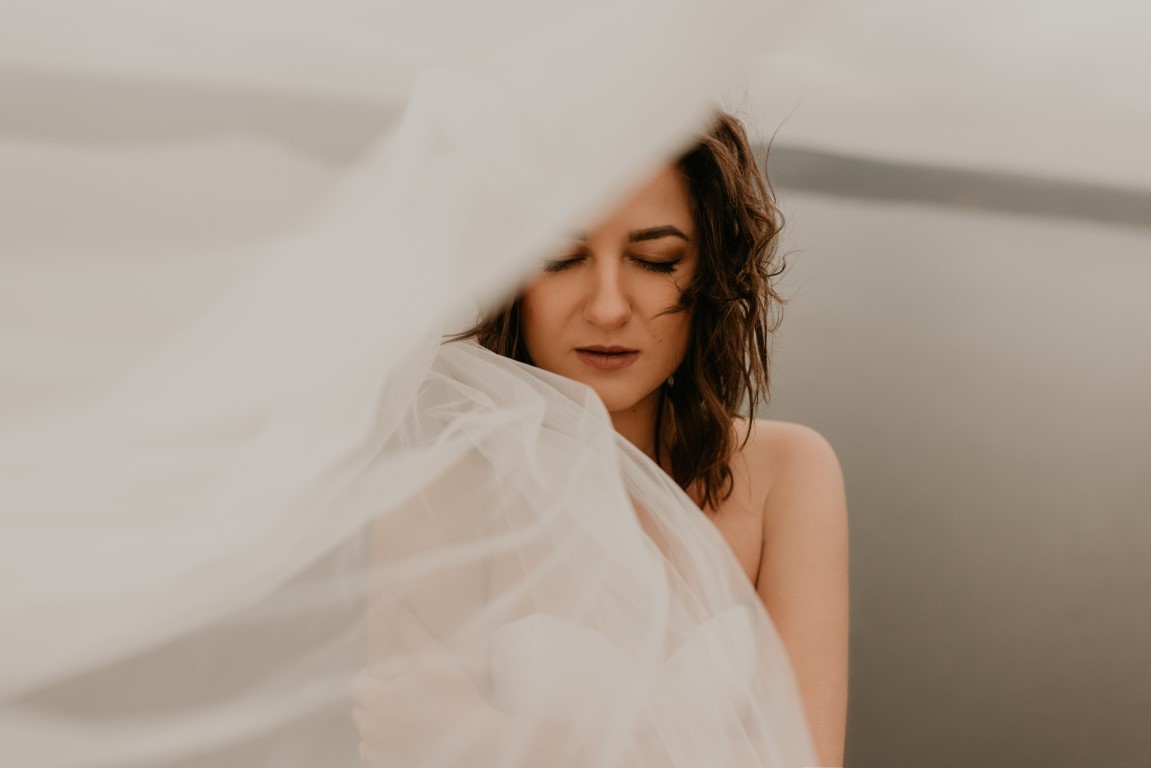 bride woman with short haircut in white wedding corset dress strapless and with a long chiffon veil on head