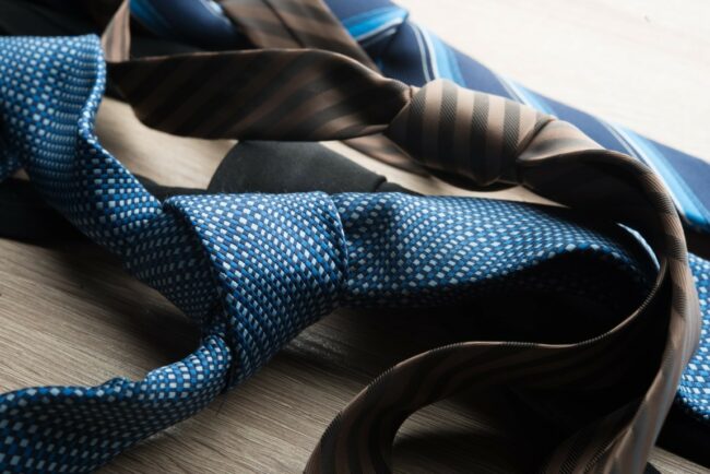 Silk neck ties on wooden background.