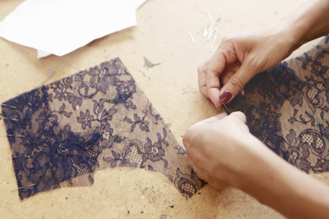 Closeup of hands sewing lace fabric