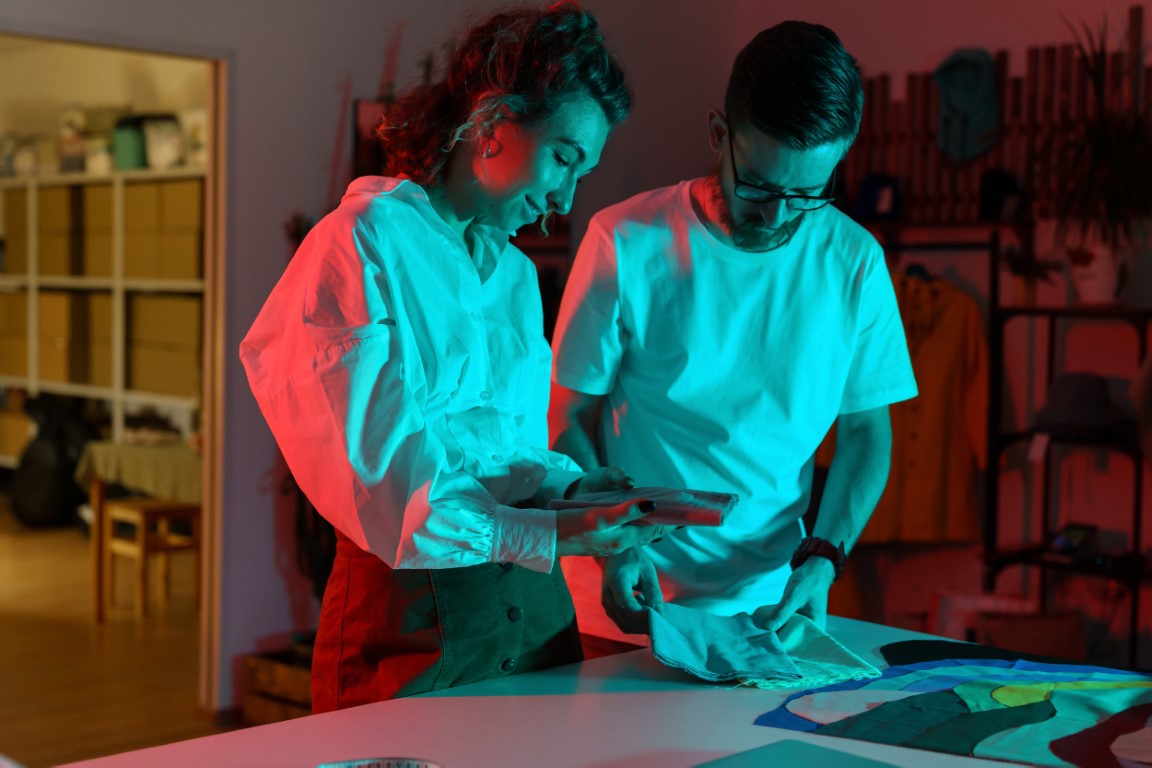 Couple of designers look through textile samples. Self-employed tailor and seamstress in workshop