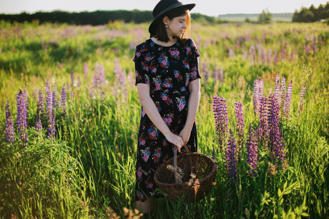Beautiful woman in vintage floral dress holding wicker rustic ba
