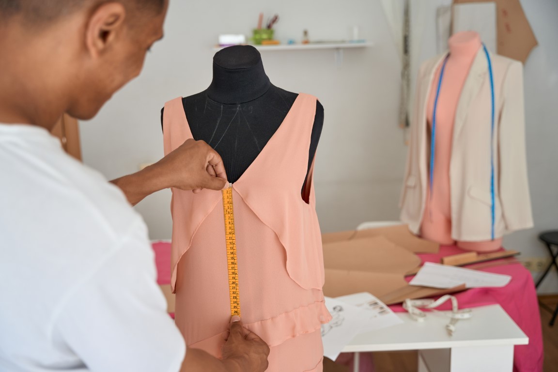 African American dressmaker measuring fabric on mannequin