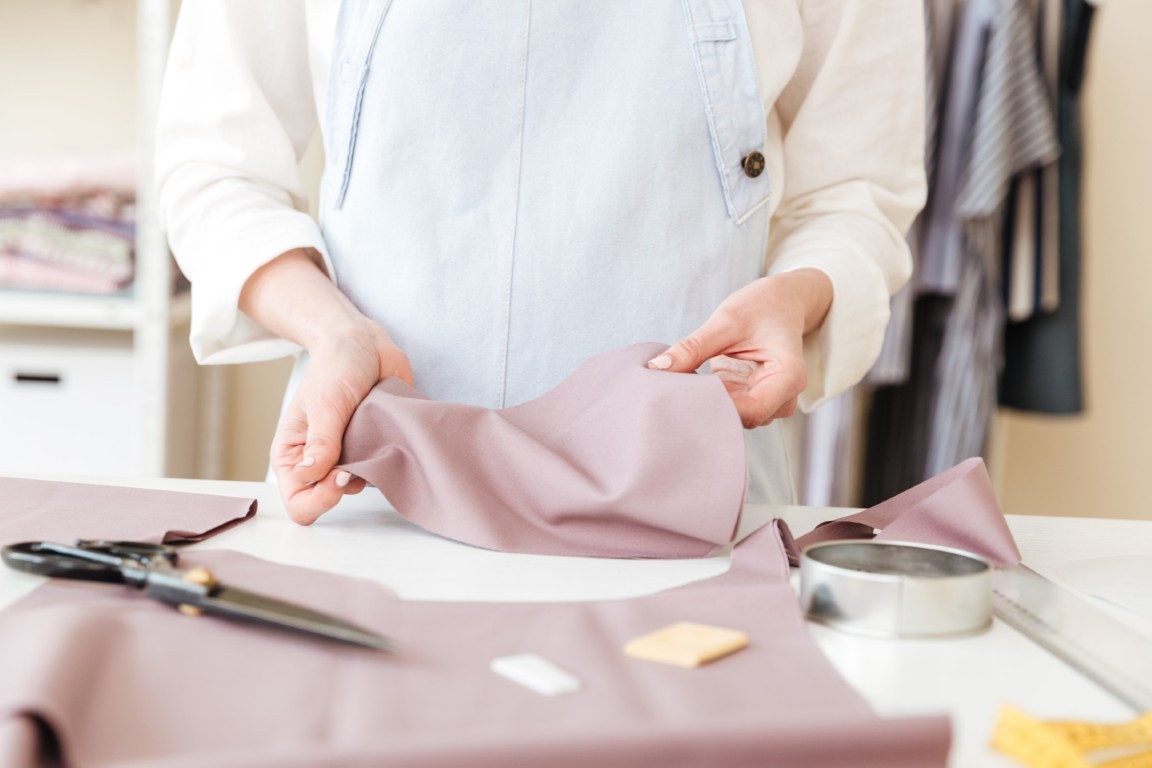 Cropped image of seamstress holding piece of fabric