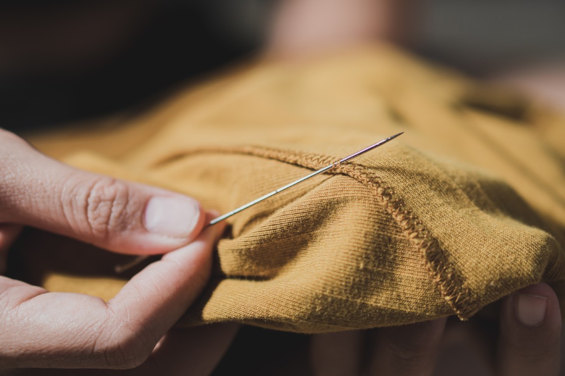 Woman fingers threading a needle